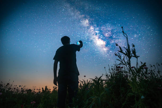 one man standing in the wild looking forward one man standing in the wild looking forward with smart phone on hand shotting photos milky way photos stock pictures, royalty-free photos & images