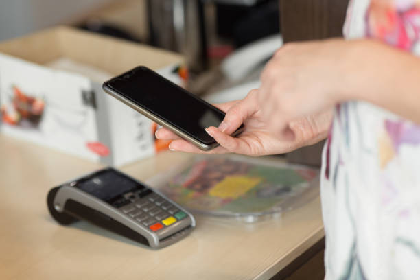 istock Woman paying bill through smartphone using nfc technology in cafe 1013414494