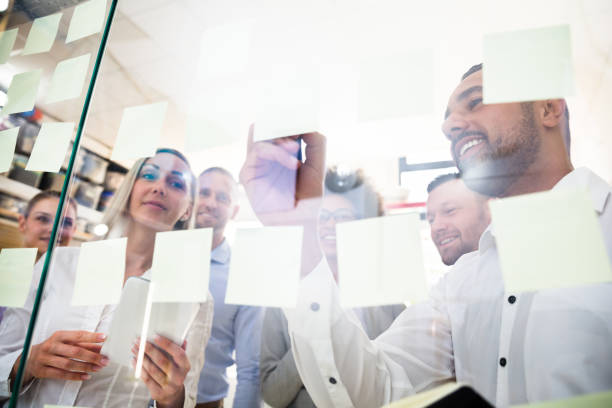 istock Group Of Businesspeople Sticking Adhesive Notes On Glass Wall 1013419378