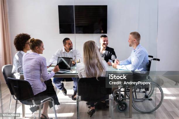 Disabled Manager Sitting With His Colleagues Stock Photo - Download Image Now - Multiracial Group, Diversity, Disability