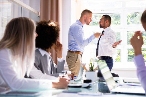 Two Male Colleagues Fighting In Office Stressed Businesspeople Sitting In Front Of Two Colleagues Fighting In Office bullying photos stock pictures, royalty-free photos & images