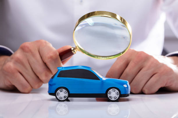 istock Businessman Holding Magnifying Glass Over Car 1013435024