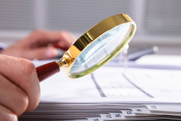 istock Businessperson Checking Invoice Through Magnifying Glass 1013435312
