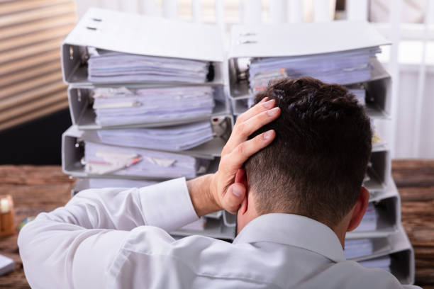 istock Stressed Businessman In Front Of Stacked Folders 1013435520