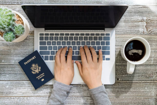 istock Person holding an American Passport while using a laptop 1013440358
