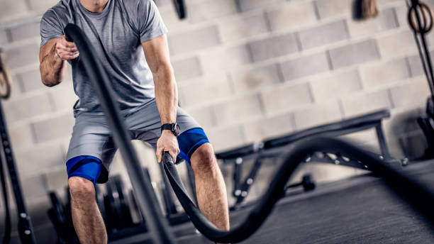 istock Unrecognizable man swinging battle ropes in a gym 1013445110