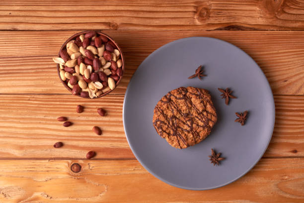 istock Fried Roasted peanut seed in clay bowl and chocolate cookies on plate. top view 1013447720