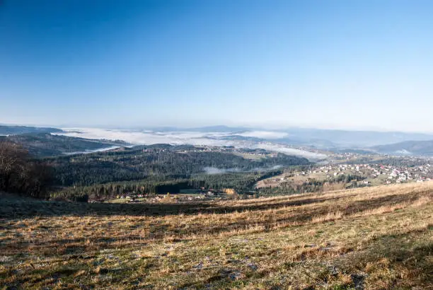 view from Ochodzita hill above Koniakow village in Beskid Slaski mountains in Poland during nice autumn morning with fog in vallesy and clear sky