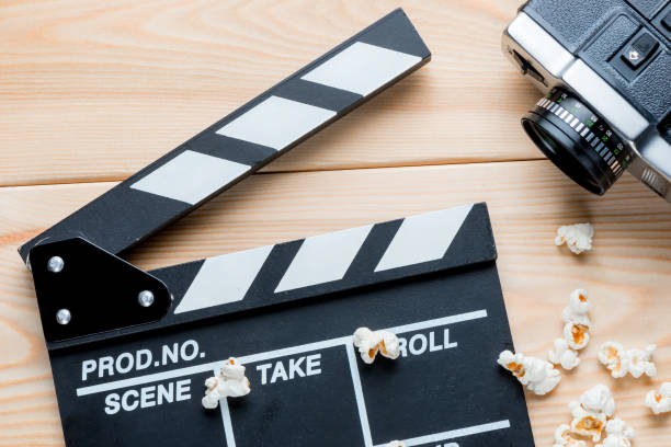 istock open video clapper, retro video camera and salted popcorn top view on wooden boards 1013455814