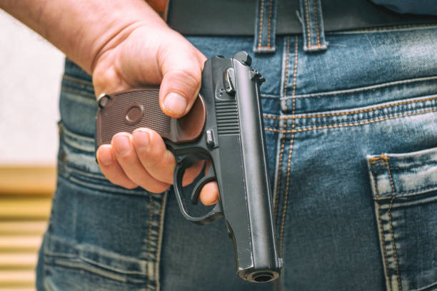 istock Man in jeans holding a gun behind his back 1013511838