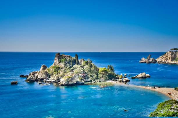 Isola Bella - the Pearl of the Mediterranean Sea Isola Bella Nature Reserve is one of the most spectacular little islands on the East coast of Sicily. It is connected to the mainland beach by a narrow sandy path. The crystal clear turquoise waters allow sea lovers to explore the treasure of the sea life and to enjoy breathtaking viewse isola bella taormina stock pictures, royalty-free photos & images