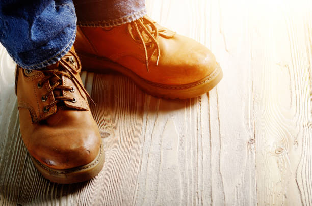 istock Carpenter feet in work boots standing on wooden floor. Place for text 1013524828