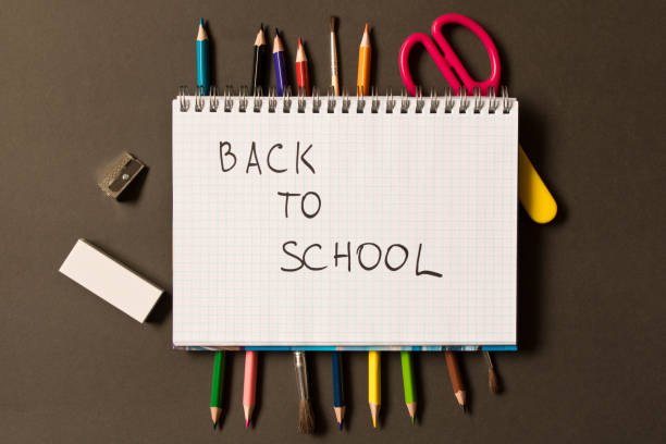istock Sign back to school in a notebook. Different school supplies on blackboard background. The concept of education 1013545404