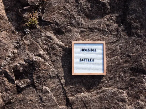 "Invisible battles" on letterboard, rocky background