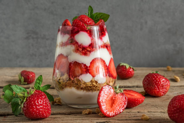 parfait aux fraises yogourt avec granola, de menthe et de petits fruits frais dans un verre sur la table en bois rustique. délicieuse cuisine saine - parfait glacé photos et images de collection