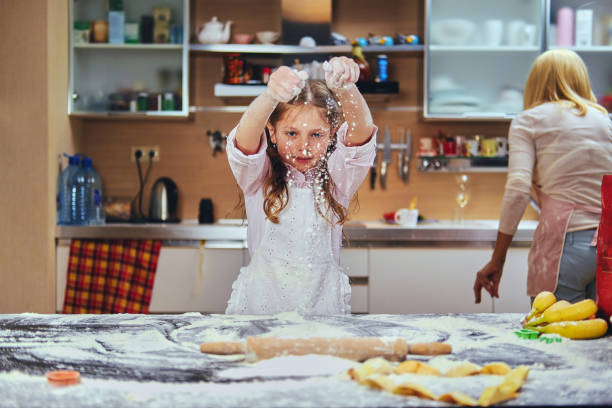 веселая маленькая девочка готовит тесто на кухне. - family with one child domestic life caucasian love стоковые фото и изображения