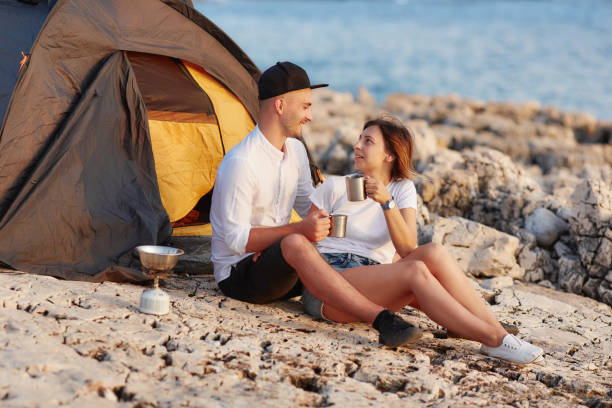 séance de couple souriant heureux face à face à une plage rocheuse sur la tente près - beach on child the photos et images de collection