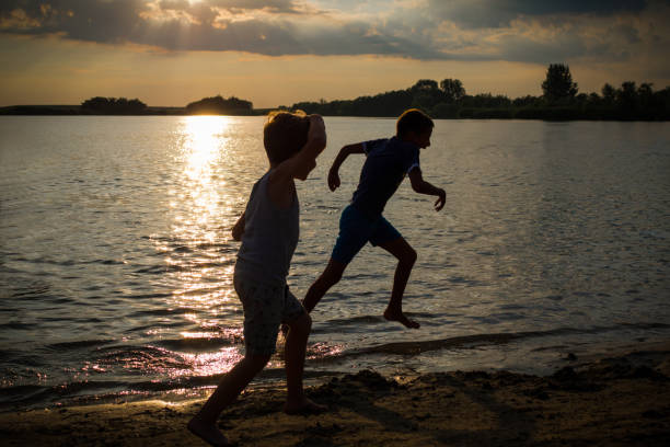 istock Happy boys running on the beach at sunset. 1013587550