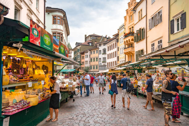 BOLZANO, ITALY - JULY 17, 2018: People shopping at a market on Piazza delle Erbe (Market Square in Italian), in the historic city center of Bolzano Market street flanked by historic buildings alto adige italy stock pictures, royalty-free photos & images