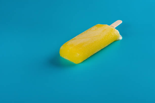 istock side view yellow popsicle starts melting on blue background 1013606248