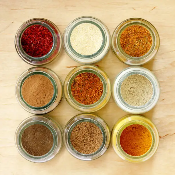 many different spices in glass jars, and a special seasoning for pilaf in the middle of a top view