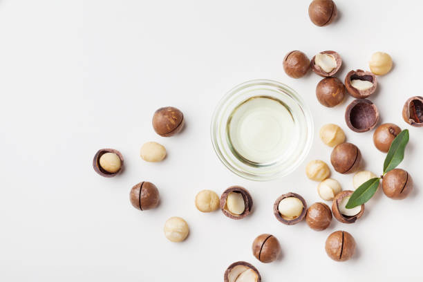 istock Organic macadamia oil and heap of nuts on white table top view. 1013613556