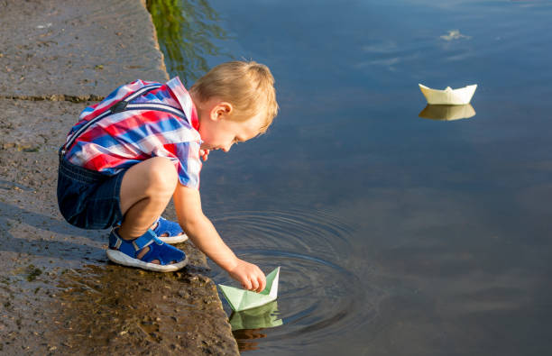 istock A little boy is launching paper boat in a water 1013625046