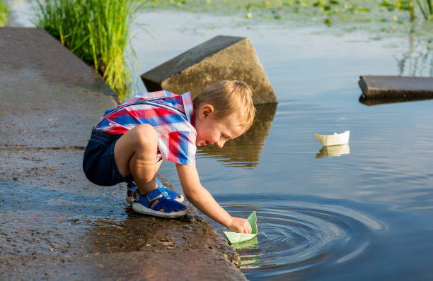 istock A little boy is launching paper boat in a water 1013625392