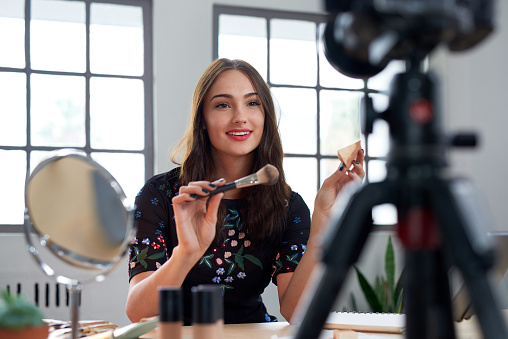 Pretty beauty vlogger recording make-up tutorial promoting product, social media marketing