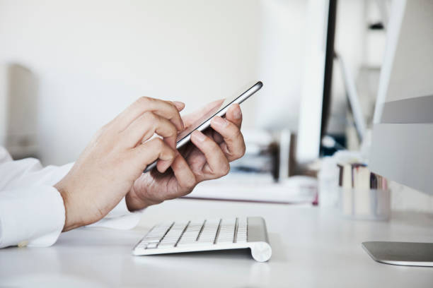 Hands of business person using a smart phone on the desk.