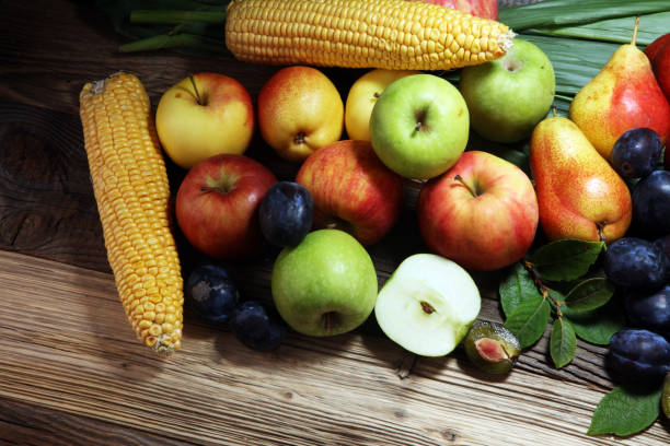Various fresh fruits. Thanksgiving pumpkin, apples, and maize on rustic background