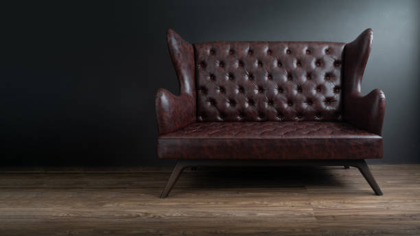 sofa schwarz leder stehen im zentrum auf betonboden gegen dunkle graue wand mit textfreiraum. vintage braune ledercouch mit grunge graue wand wohnzimmer. - armchair chair leather black stock-fotos und bilder