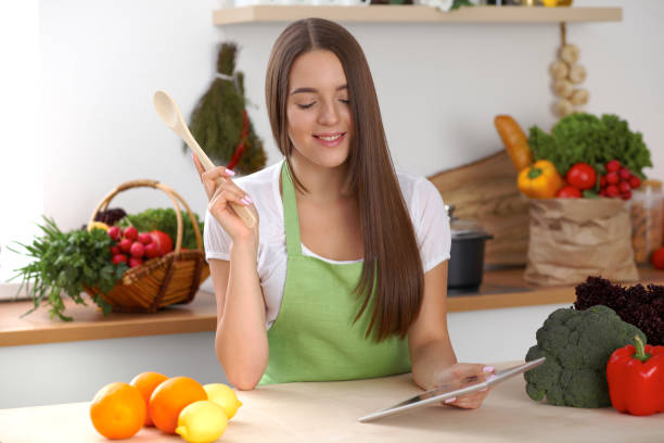 istock Young woman using tablet computer while cooking in kitchen. Householding, tasty food and digital technology in lifestyle concepts 1013675202