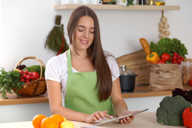 istock Young woman using tablet computer while cooking in kitchen. Householding, tasty food and digital technology in lifestyle concepts 1013675218
