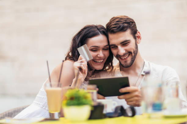 istock Beautiful couple having coffee on a date, using digital tablet and credit card for online shopping 1013675814