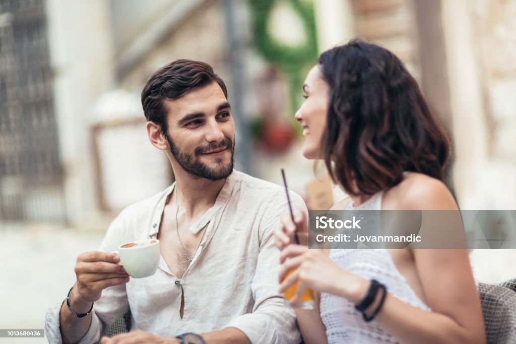 Young tourists having coffee at cafe and reading map Love At First Sight Stock Photo