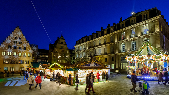 People at the Christmas market in Place du Château of Strasbourg, considered the capital of the historical region of Alsace. The city is the official seat of the European Parliament.