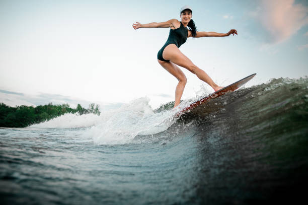 istock Rear view young active woman riding on the orange wakesurf 1013684624