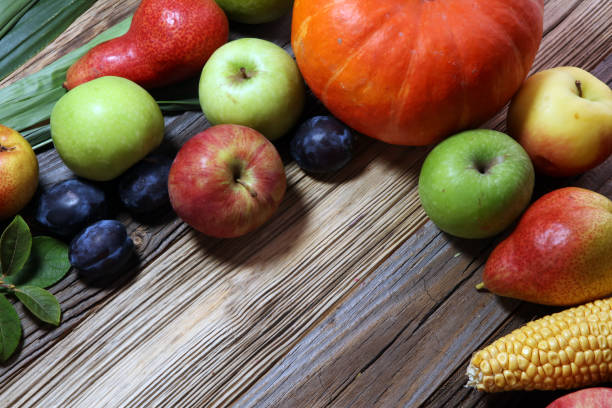 Various fresh fruits. Thanksgiving pumpkin, apples, and maize on rustic background