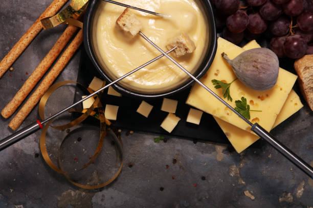 istock Gourmet Swiss fondue dinner on a winter evening with assorted cheeses on a board alongside a heated pot of cheese fondue 1013695470