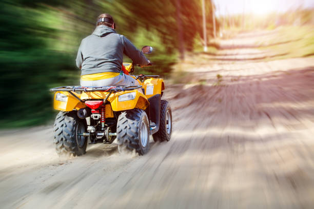 A man riding ATV on a sand road, back view A man riding ATV on a sand road, back view. motorcycle 4 wheels stock pictures, royalty-free photos & images