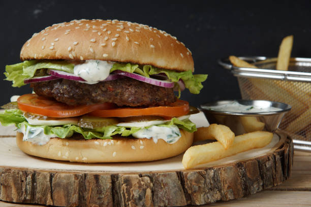 istock Large juicy burger with beef chops, salad, cheese and sauce 1013718052