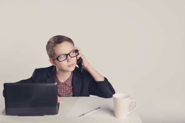 istock Cute little boy in a suit talking on the phone 1013721774
