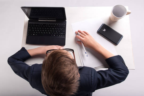 istock Young businessman kid sitting at the table top view 1013721872