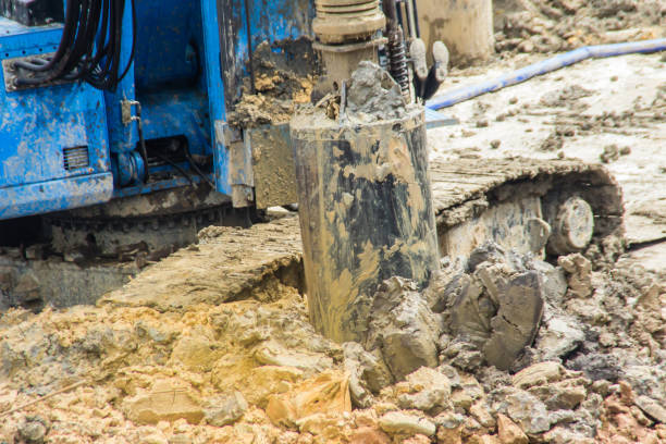 istock Hydraulic drilling machine is boring holes in the construction site for bored piles work. Bored piles are reinforced concrete elements cast into drilled holes, also known as replacement piles. 1013721898