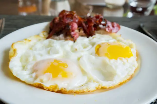 Breakfast concept. Close up of fried egg and bacon slices on the plate