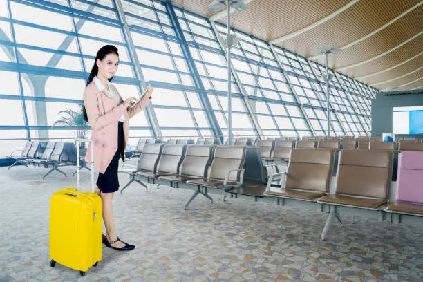 Portrait of Caucasian businesswoman holding a digital tablet while standing with a luggage in the airport lounge