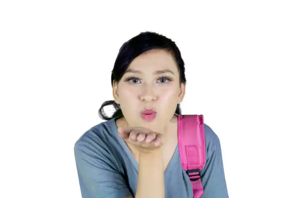 Picture of Caucasian female college student blowing an air kiss at the camera, isolated on white background