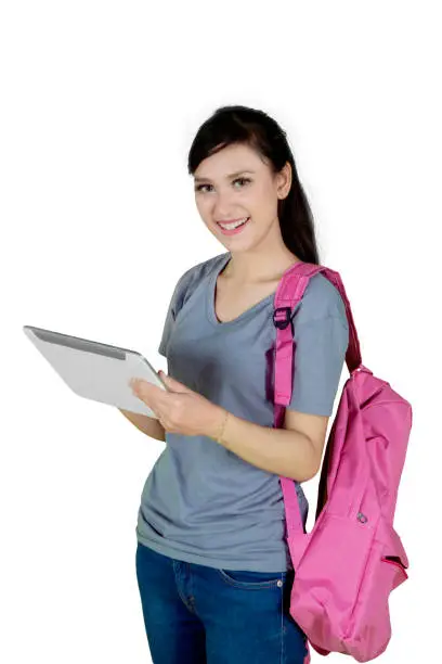 Portrait of a Caucasian female college student carrying a bag while using a digital tablet, isolated on white background