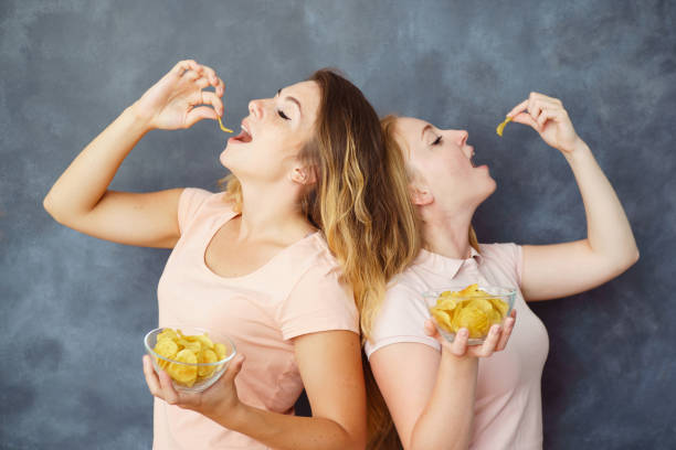 istock Two cute young women eating potato chips 1013734996